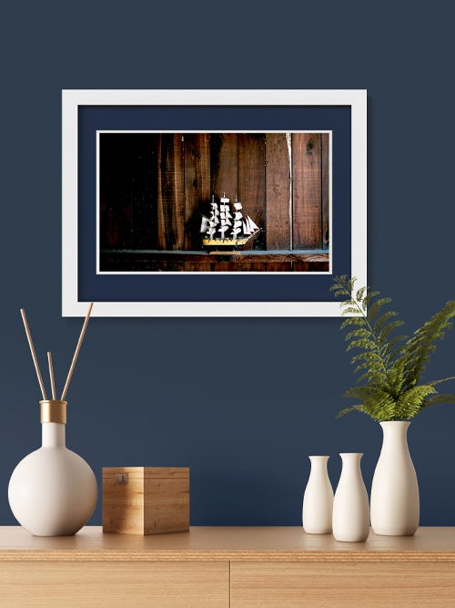 A navy mat board with a white frame on a navy wall A navy mat board with a white frame on a navy wall