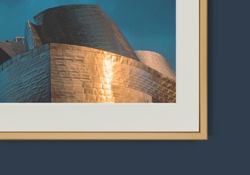 White mat board with a gold frame on a navy wall White mat board with a gold frame on a navy wall