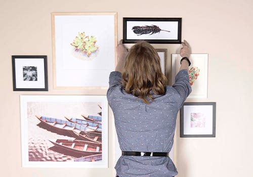 A woman setting up a gallery wall A woman setting up a gallery wall