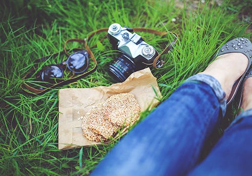 A photo of a person lounging in grass with a camera A photo of a person lounging in grass with a camera