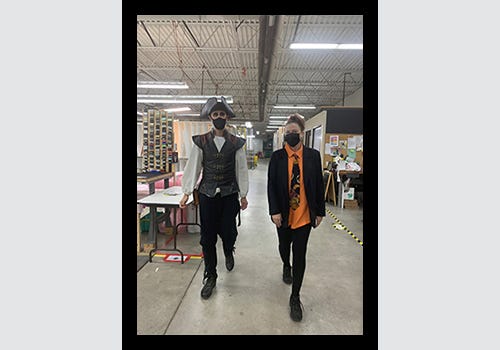 Employees in Halloween costume walking through American Frame's production facility.