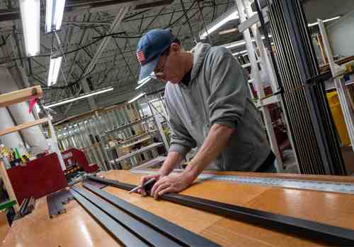 A team member inspects lengths of wood frames before cutting them. A team member inspects lengths of wood frames before cutting them.
