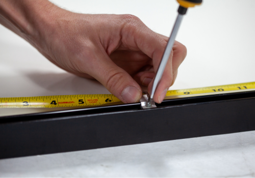 Using a screwdriver to tighten hardware in a metal picture frame.