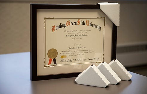 College diploma with a black frame and cream mat that has corrugated cardboard corners on the edges for protection