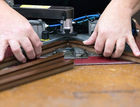 V nails being applied with an underpinner to securely join two sections of a wood picture frame