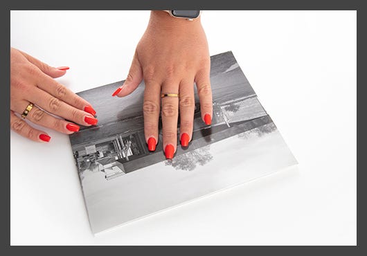 Flattening photograph to self-adhesive mounting board