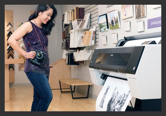 Photographer watching prints come off a wide format printer Photographer watching prints come off a wide format printer